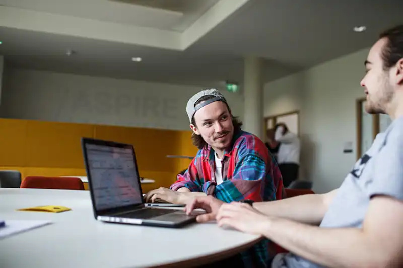 Marketing students working at a laptop.