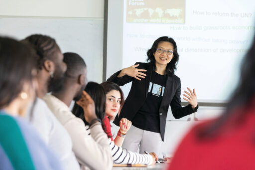 A lecturer talks to students in a seminar room.